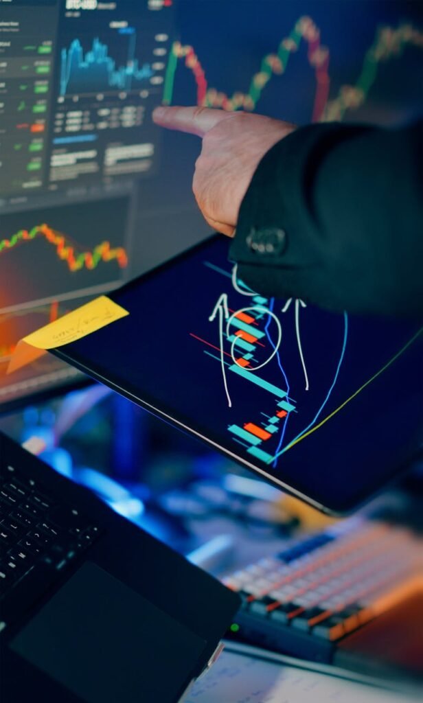 investor analyzing charts on tablet and laptop screens